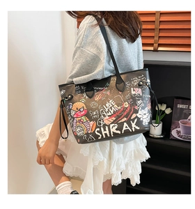 Detail of a large black tote bag featuring colorful graffiti prints and cartoon bear patterns