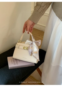 Détail d'un sac en cuir beige avec boucle dorée et foulard en soie décoratif