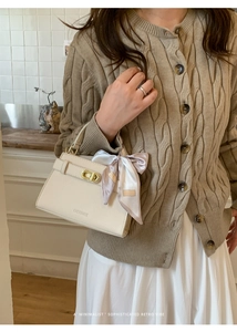 Sac chic en cuir beige avec foulard et boucle dorée sur pull en maille tressée