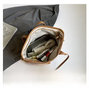 Top view of spacious brown leather tote interior with daily essentials and gadgets