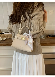 Détail d'un sac en cuir beige avec fermoir métallique et foulard en soie décoratif
