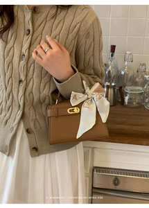 Détail d'un sac Kelly en cuir marron avec un foulard en soie et un fermoir doré