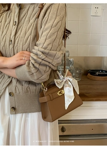 Détail d'un sac à main en cuir marron avec boucle dorée et foulard en soie élégant