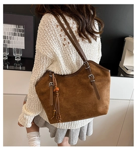 Detail of vintage brown tote bag with beaded tassel and soft suede texture on shoulder