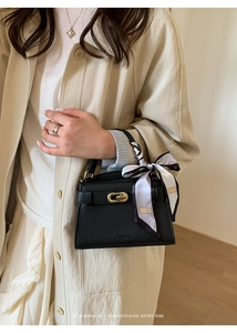 Gros plan d'un sac en cuir noir grainé avec boucle dorée et foulard en soie décoratif