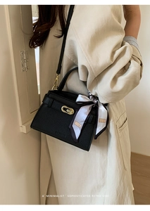 Détail du sac en cuir grainé noir avec fermoir doré et foulard en soie décoratif