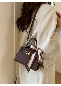 Détail du sac Kelly en cuir marron café avec fermoir doré et ruban en soie