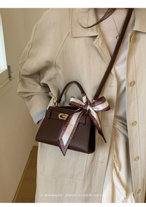 Détail du sac Kelly marron foncé texture lychee avec boucle dorée et foulard en soie fleurie