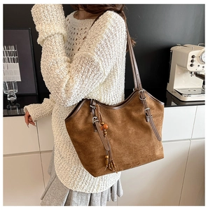 Detail view of large brown vintage tote bag with wooden bead tassel and adjustable strap