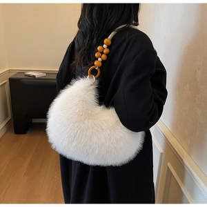 Detail of white faux fur crescent bag with decorative orange wooden beads on strap