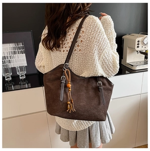 Macro shot of dark brown suede tote bag featuring a decorative ethnic beaded tassel