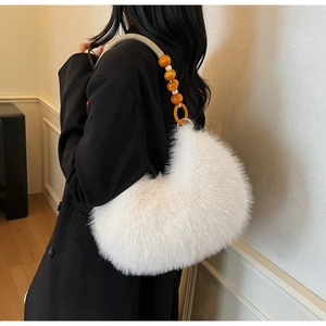Detailed close-up of white plush crescent bag featuring distinctive beaded shoulder strap