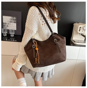 Detail of vintage dark brown suede tote bag featuring a wooden bead tassel and silver hardware