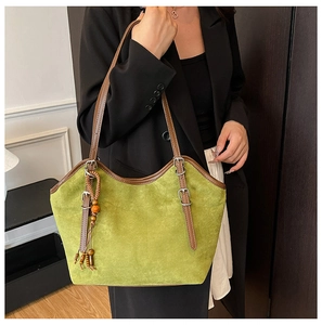 Detail of green suede tote bag with brown leather strap and retro beaded pendant