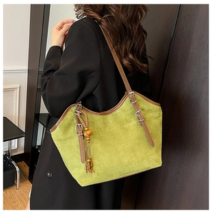 Detail of green suede tote bag featuring brown leather trim and wooden bead tassel