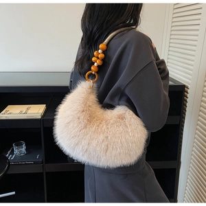 Detail of plush beige shoulder bag featuring chunky orange wooden bead handle and soft fur