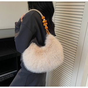 Detail of plush faux fur handbag with orange beaded strap against a minimalist interior