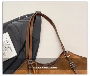 Detail of adjustable leather shoulder straps with dark grey metal buckles on a brown tote