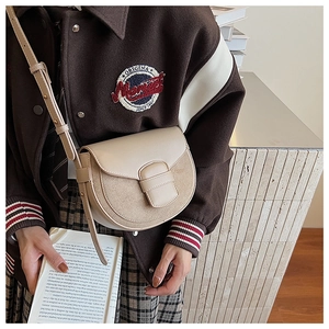 Detalle del bolso de silla crema con hebilla decorativa y costuras de cuero liso