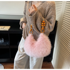 Close-up of pink faux fur hobo bag featuring unique orange wooden beaded handle detail
