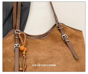 Detail of brown suede tote bag featuring adjustable leather straps with silver metal buckles