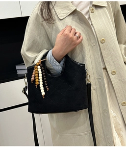 Close-up of black quilted bucket bag with colorful beaded tassels and slim shoulder strap