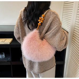 Detailed view of plush pink crescent bag with chunky orange beaded shoulder strap