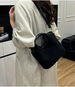 Detail of black quilted bucket bag with round cutout handle and detachable shoulder strap