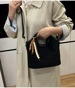 Close-up of quilted black suede bucket bag with decorative wooden bead pendant