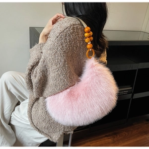 Detail of pink faux fur shoulder bag with orange beaded handle and crescent shape