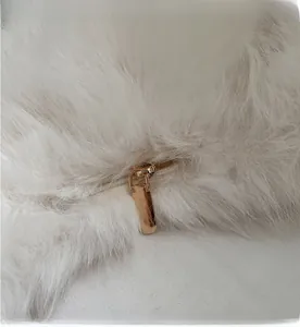 Detail of smooth gold metal zipper on white faux fur shoulder bag texture
