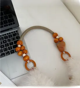 Detailed view of plush handbag handle with braided cord, wooden beads, and faux fur texture