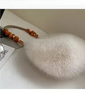 Close-up of fluffy white faux fur shoulder bag featuring orange wooden bead strap
