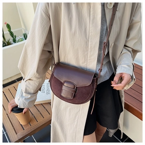 Detalle de bolso de silla marrón oscuro con costuras de gamuza en contraste y correa ajustable