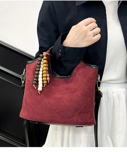 Detail of wine red quilted bucket bag with matte texture and decorative wooden beads