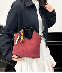 Close-up of burgundy quilted bucket bag with retro wooden bead charms and matte texture