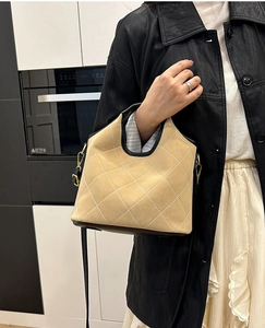 Close-up of quilted suede bucket bag featuring black leather trim and metal hardware