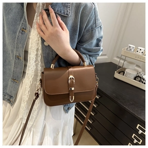 Detail of vintage brown leather bag with golden metallic buckle and adjustable strap