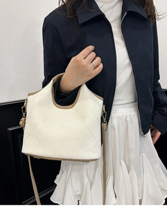 Detail of quilted bucket bag featuring white PU leather and brown trim with metal hardware