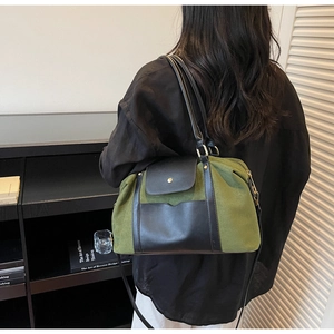 Detail der Tasche aus olivgrünem Wildleder und schwarzem Leder mit Goldbeschlägen