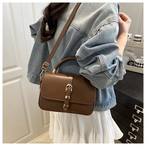 Detailed side view of vintage brown lychee textured shoulder bag with golden belt buckle