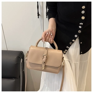Détail d'un sac à main beige en similicuir avec boucle en métal doré et bandoulière