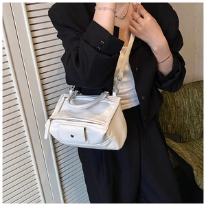 Detail view of white asymmetric leather crossbody bag with multiple zippers and pockets