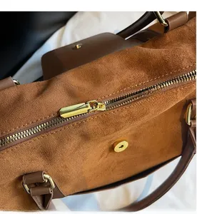 Détail de la fermeture éclair dorée et de la texture en daim givré du sac marron