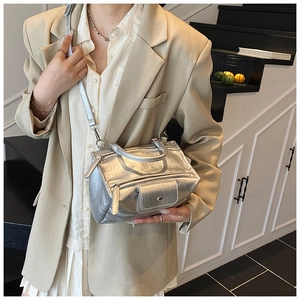 Detailed view of silver metallic textured crossbody bag with top handles on a model