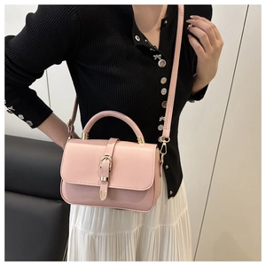 Pink leather mini crossbody bag with gold buckle shown on model for size perspective