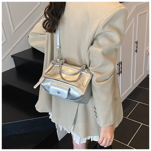 Silver textured crossbody bag with a unique geometric shape shown worn by a model