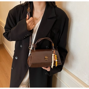 Detail of vintage brown leather handbag featuring colorful bead charms and gold hardware