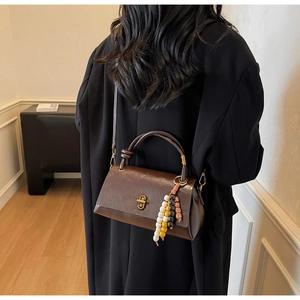 Detail of vintage dark brown faux leather bag with metal twist lock and beaded charm