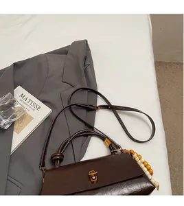 Detail of vintage brown leather handbag with gold twist lock and beaded tassel charm